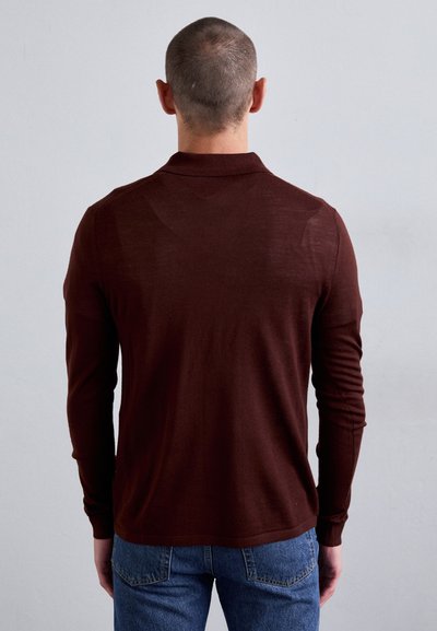 Braunes Langarm-Polohemd, gestrickte Textur, weiches Material, gerippte Bündchen, Kragen-Detail, getragen mit blauen Jeans.