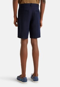 Námořnické lněné kraťasy s volným střihem, dvěma zadními kapsami a bočními švy. V kombinaci s modrými pohodlnými botami na šněrování a bílou podrážkou.