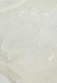 White lace fabric featuring intricate floral embroidery with clear beads, creating a textured and detailed design.