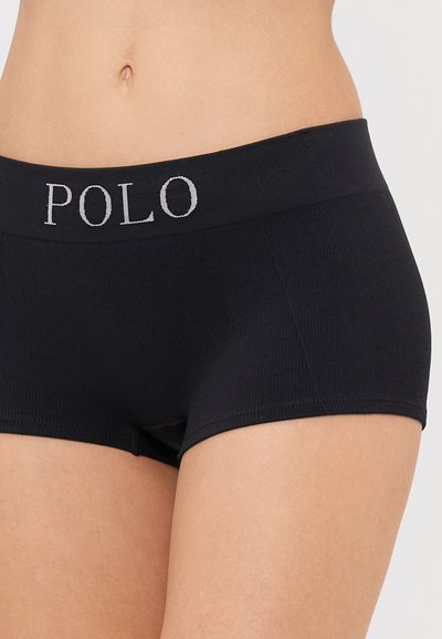 Črne rebraste kratke hlačke z elastičnim pasom, na katerem je v srebrni barvi izvezena beseda "POLO". Mehka tekstura, prilegan dizajn.