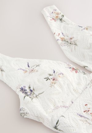 White floral-patterned top with textured surface and wide straps, featuring pastel colored flowers and a delicate leaf pattern.