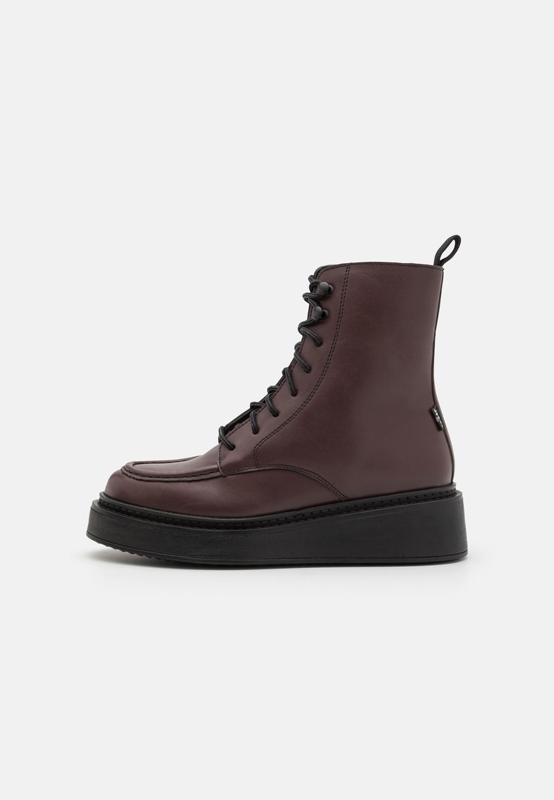 Botas de tornozelo em couro bordeaux com cordões pretos, apresentando uma biqueira arredondada e uma sola plataforma grossa preta para maior altura.
