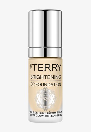 Luchtdichte pompflacon van CC foundation; heldere glazen basis, gouden vloeistof, zilveren dop, bloemenontwerp op het etiket, 30 ml capaciteit.