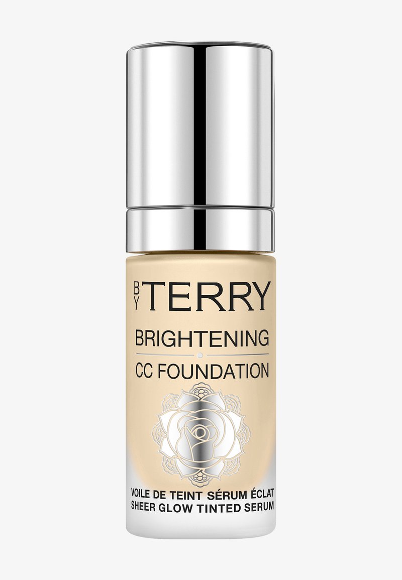 Flacone a pompa senza aria per fondotinta CC; base in vetro trasparente, liquido dorato, cappuccio argentato, design floreale sull'etichetta, capacità di 30 ml.