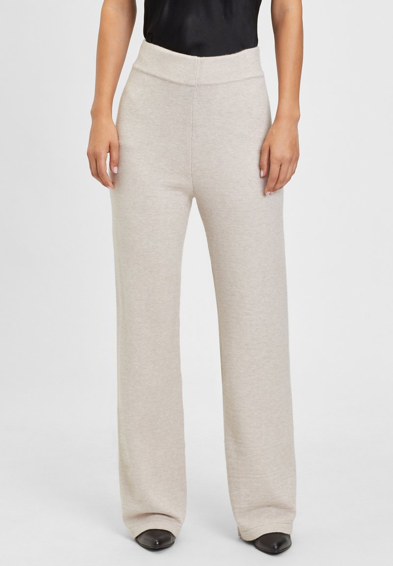 Cremefarbene weite Hose mit hohem Bund, aus weichem, strukturiertem Stoff; zeichnet sich durch eine glatte Oberfläche und minimalistisches Design aus.