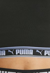 Schwarzer Sport-BH aus strukturiertem Material, mit einem hellblauen und schwarzen Bund, auf dem der Markenname "PUMA" und das Logo abgebildet sind.