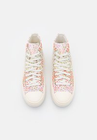 Wysokie sneakersy z białą cholewką z płótna, zdobione kolorowym nadrukiem w kropki w odcieniach różu, pomarańczy i zieleni. Białe sznurowadła i gumowe podeszwy.