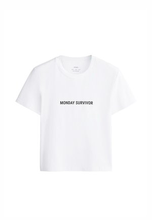Wit T-shirt met korte mouwen, ronde hals en zwarte tekst "MONDAY SURVIVOR" centraal op de voorkant gedrukt.