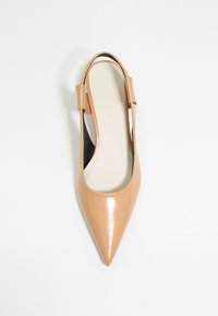 Nudové lakované slingback ploché topánky s špicatou špičkou, výrezmi po bokoch a hladkým textúrovaným povrchom. Interiér obsahuje krémovú stielku.