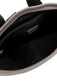 Interior de bolsa de ante gris con una textura suave y lisa; forro negro; bordes cosidos; cierre de broche magnético.