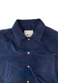 Camicia button-up blu navy in cotone. Caratterizzata da un colletto classico, una tasca sul petto e bottoni di colore chiaro. Texture stropicciata.