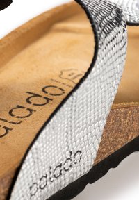 Silver textured sandal with a cork footbed and dark rubber sole. Features a scale pattern on the upper and a logo on the insole.