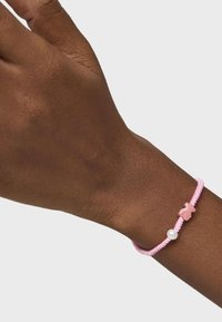 Bracciale intrecciato rosa con un charm a forma di orsetto rosa e un accento di perla bianca. Il bracciale è texture e si adatta comodamente al polso.