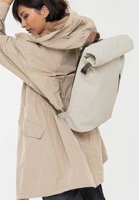 Rugzak met rolklep in lichtgrijze stof met leren accenten; beschikt over verstelbare banden, een gestroomlijnde vorm en een zijvak met rits.