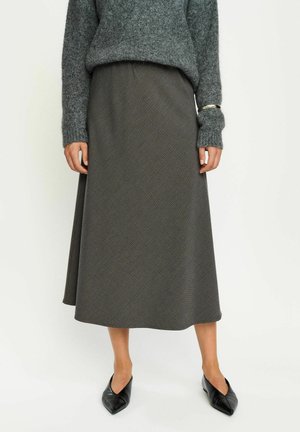 Gray sweater with textured knit paired with a dark, patterned, midi-length skirt. Black pointed toe shoes complete the outfit.