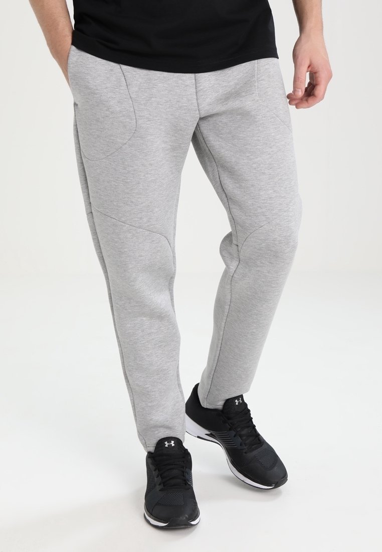 Grå sweatpants med en slät yta, avsmalnande bendesign och framträdande sömdetaljer; bärs med svarta träningsskor.
