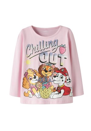 Chemise rose clair à manches longues avec trois chiots dessinés partageant une boisson à l'ananas, texte "Chilling Out" et petites illustrations de soleil et de fraise.