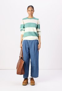 Prugasta jopica v teal in krem barvi, ohlapne modre jeans hlače, rjava usnjena torba in rjave platforme.