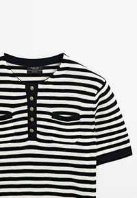 Randig svart och vit bomullsskjorta med rund halsringning, femknapps placket och två framfickor med svart kant.