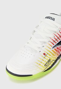 Witte sportieve schoen met een leren bovenwerk met textuur. Kenmerkt zich door een gradientontwerp in rood en geel, zwarte accenten en een felgroene zool.