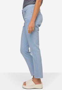 Jasnoniebieskie dżinsowe spodnie o slim fit, z bocznymi przeszyciami, tradycyjnymi kieszeniami i średnim stanem.