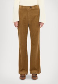 Pantaloni din catifea brown cu un design evazat, având închidere cu nasture în față și buzunare laterale. Textură netedă și detaliu cu striații verticale.