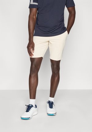 Μπλε σκούρο κοντομάνικο πουκάμισο με ριγέ λεπτομέρειες και μπεζ σορτς. Λευκά αθλητικά παπούτσια με μπλε λεπτομέρειες και λευκές κάλτσες. Ένα casual ντύσιμο για εξωτερικές δραστηριότητες.