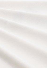 Tessuto di cotone di un bianco puro, con una texture liscia e leggere ondulazioni, che riflettono la luce in forme morbide e sottili.