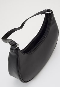 Černá kožená kabelka s zakřiveným designem, plochým dnem a zipovým uzávěrem. Obsahuje jeden nastavitelného ramenní popruhu a stříbrné kovové prvky.