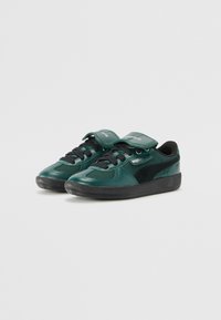 Groene leren sneakers met zwarte accenten, textuur oppervlak, vetersluiting en klittenbandsluiting. Rubberen zool met merklogo op de zijkant.