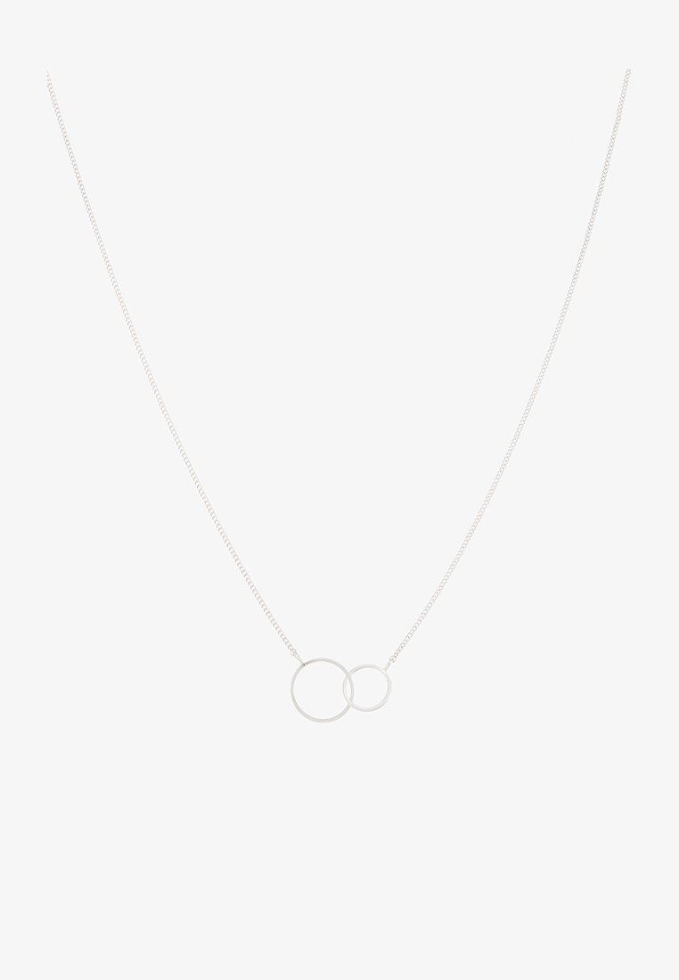 Collar de plata que presenta dos círculos entrelazados, uno más grande y otro más pequeño, en una cadena delgada. Textura suave con un diseño minimalista.