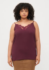 Burgundy camisole with adjustable straps, featuring a V-neckline adorned with delicate lace trim and a soft, textured fabric.