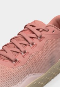 Κοντινό πλάνο ροζ αθλητικού παπουτσιού με υφασμάτινη υφή, κορδόνια στο ίδιο χρώμα, επενδεδυμένο γιακά και μπεζ καουτσούκ σόλα με σχέδιο για καλύτερο κράτημα.