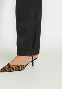 Luipaardprint pointed toe pumps met stiletto hak en zwarte band, gecombineerd met zwarte op maat gemaakte broek met een strakke zoom.