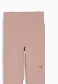 Leggings pour femmes Puma de couleur rose pâle, dotés d'une taille haute, d'une texture lisse et d'un petit logo dans une teinte plus foncée sur la jambe gauche.
