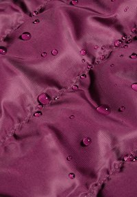 Wodoodporna, teksturowana tkanina w głębokim fiolecie z widocznymi kroplami wody i pikowanym wzorem szwów. Gładka powierzchnia.