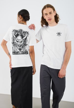 White cotton t-shirt featuring a large black graphic of a mythical mask on the back and a small logo on the front left chest.