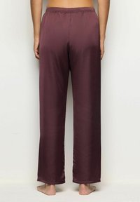 Burgundy satiin pajamasukset, joissa on rento malli, joustava vyötärö ja leveät lahkeet. Ne on varustettu sileällä pinnalla ja huolitelluilla hihoilla.
