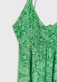 Vihreä mekko, joka on valmistettu kevyestä kankaasta ja jossa on valkoinen paisleymuotoilu. Sen olkaimet ovat ohuet ja kuminauhakujassa on rento istuvuus.