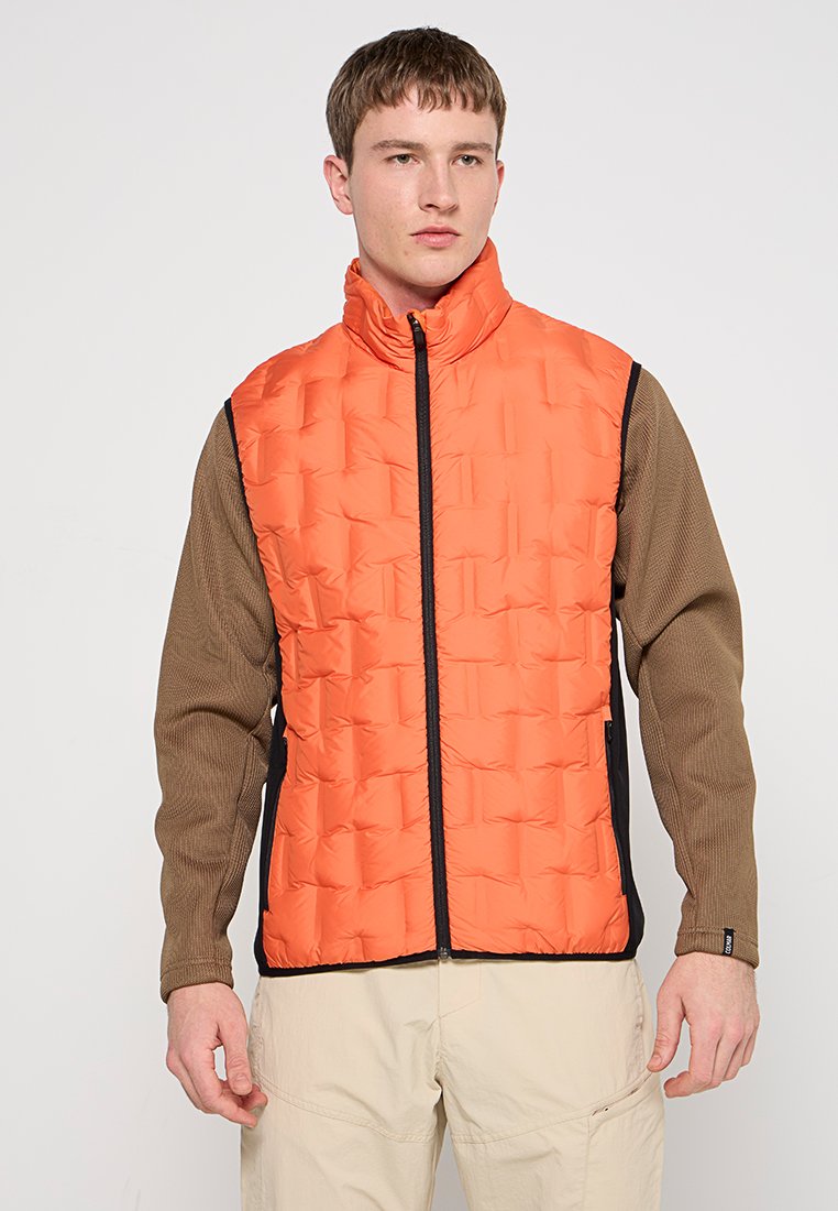 Puffige orange Weste mit hohem Kragen, Reißverschluss vorne und schwarzen Akzenten; kombiniert mit einem braunen strukturierten Langarmshirt. Einfaches Design.