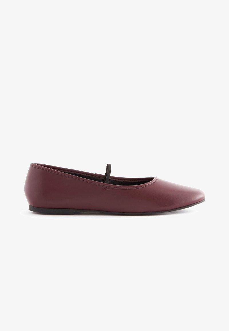 Ballerines en cuir bordeaux avec un bout rond, une fine sangle élastique noire sur le dessus du pied, et une semelle en caoutchouc plate. Texture lisse.