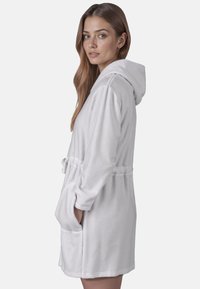 Witte fleece badjas met capuchon, ceintuur in de taille en zakken. Zachte textuur; knielang ontwerp met lange mouwen.