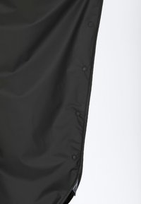 Musta nailonikangas, jossa on sileä pinta, ja jossa on nepparit yhdellä reunalla sekä ommeltu reuna. Yksinkertainen, toiminnallinen muotoilu.