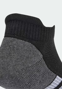 Calcetines tobilleros en negro y gris con un borde acanalado, tejido texturizado y una franja blanca horizontal en la base. Detalles de costura reforzada.