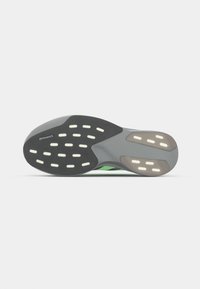Black and green athletic shoe outsole, featuring a textured rubber surface with white traction dots and a logo on the heel area.