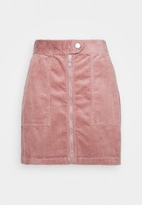 Jupe en velours côtelé rose avec une fermeture éclair à l'avant, deux poches avant et une large ceinture. Présente une texture à côtes verticales et un tirette de fermeture éclair circulaire.