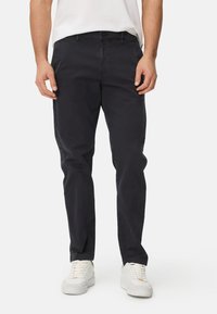 Navy blue cotton trousers with a straight fit, standard pockets, and a button closure. Worn with white sneakers.