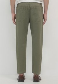 Pantaloni in cotone verde oliva a gamba dritta, con quattro tasche e vita. Indossati con scarpe in pelle marrone.