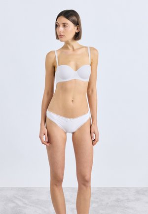 Soutien-gorge blanc à bonnets lisses et fines bretelles, assorti à une culotte blanche bordée de dentelle avec un petit nœud au centre.