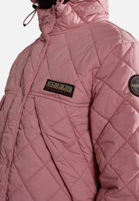 Vycpaná růžová bunda s prošívaným designem, vybavená vysokým límcem, stahovacími šňůrkami a logovými nášivkami na hrudi a rukávu.